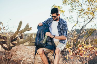 Uzun yürüyüşe çıkan kimse adam su şişesi sırt çantasına koyar. Kavram hiking macera keşfetmek