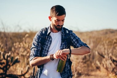 Kol saati çölde seyir yakışıklı bir erkek hiker portresi