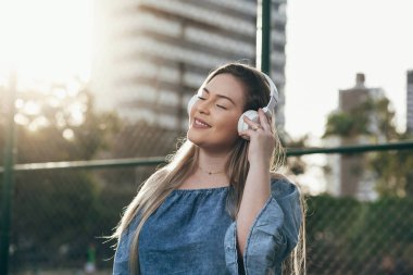 Genç kadın sokakta kulaklık ile müzik dinlemek