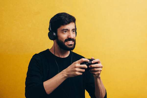 Молодой человек играет в видеоигры на жёлтом фоне
