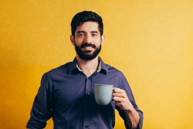 Yakışıklı adam sarı arka plan üzerinde kahve içme portresi