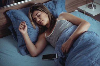 teknoloji ve insan kavramı - evde yatakta gece uyku smartphone ile genç kadın
