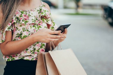 Bir akıllı telefon ile alışveriş ve çantaları taşırken alışveriş kadın el
