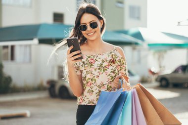 Bir akıllı telefon ile alışveriş ve çantaları taşırken alışveriş kadın el