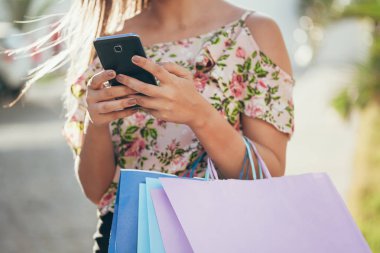 Bir akıllı telefon ile alışveriş ve çantaları taşırken alışveriş kadın el