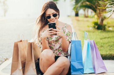 Bir akıllı telefon ile alışveriş ve çantaları taşırken alışveriş kadın el