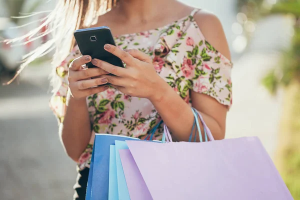 買い物客の女性手スマート フォンと買い物と袋を運ぶ — ストック写真