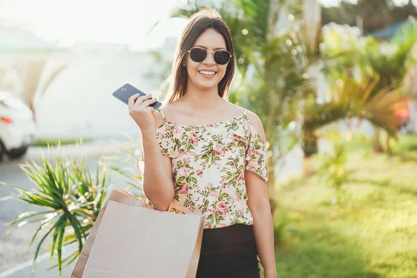 Shopper woman hand shopping with a smart phone and carrying bags