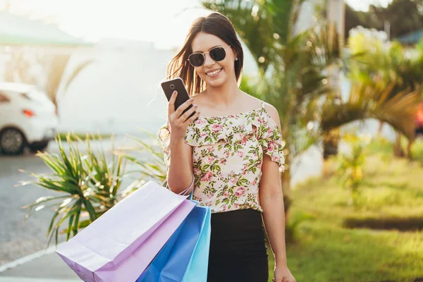 買い物客の女性手スマート フォンと買い物と袋を運ぶ — ストック写真