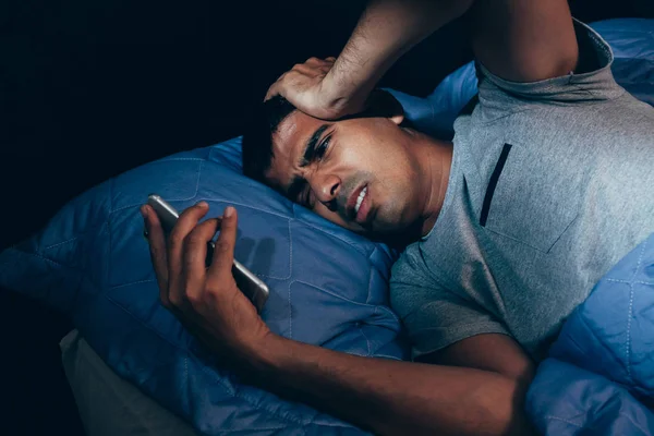 晚上睡觉的男人在卧室里被手机吵醒 — 图库照片