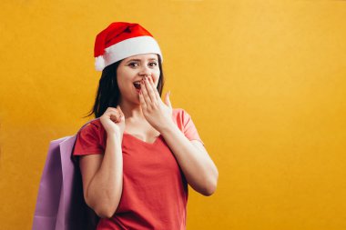 Alışveriş torbaları renk arka plan üzerinde tutarak Noel Baba şapkası ile güzel kadın