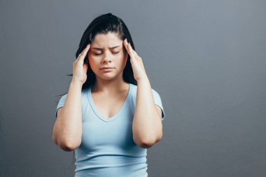 Gri arka plan üzerinde izole bir baş ağrısı muzdarip rahatsız bir kadın portresi