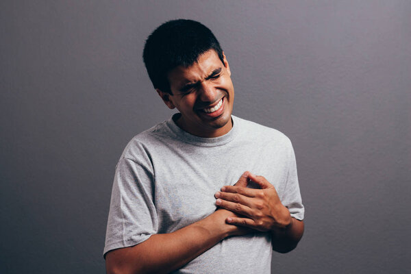People, healthcare and problem concept - close up of man suffering from heart ache over gray background