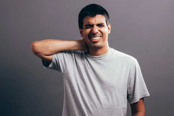 Portrait de jeune homme avec douleur au cou sur fond gris — Photo