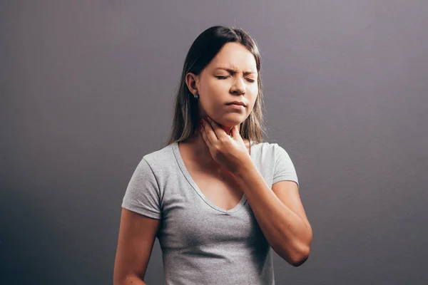 Mujer que sufre de dolor de garganta sobre fondo gris — Foto de Stock