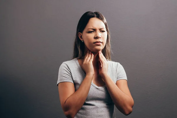 Mulher que sofre de dor de garganta sobre fundo cinza — Fotografia de Stock