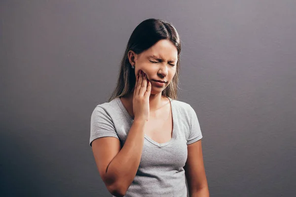 Unglückliche Frau fühlt Schmerzen auf ihren Zähnen isoliert auf grauem Hintergrund — Stockfoto