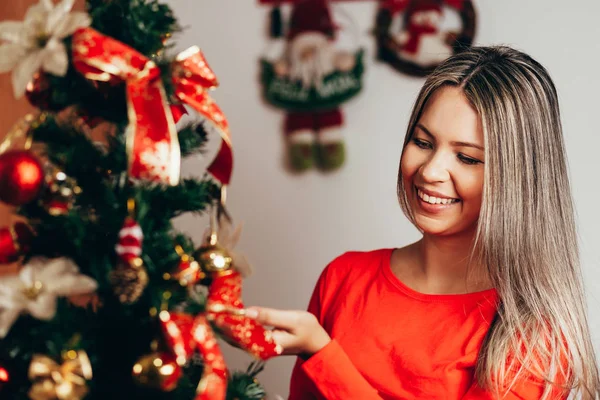 Happy woman Decorating Christmas Tree in their Home. Smiling Woman Celebrating Christmas or New Year. Christmas Tree Decoration.