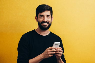 Cep telefonuyla sarı arka plan üzerinde izole genç portresi