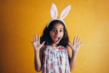 Renk arka plan üzerinde Paskalya gününde tavşan kulakları giyen sevimli küçük çocuk