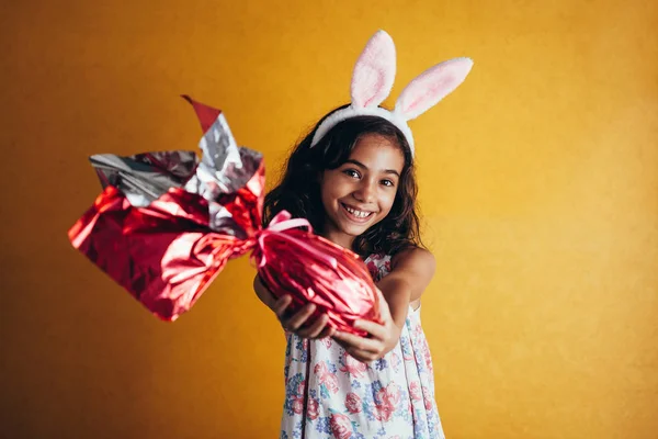 可爱的小孩戴兔子耳朵在复活节那天的颜色背景 女孩拿着巧克力复活节蛋 — 图库照片