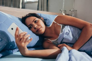 Kadınlar geceleri uyumadan önce yataktaki akıllı telefonu kullanırlar. Mobil bağımlılık kavramı.