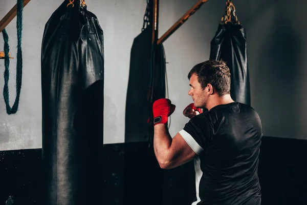 Боец тренируется в тяжелой сумке в спортзале — стоковое фото