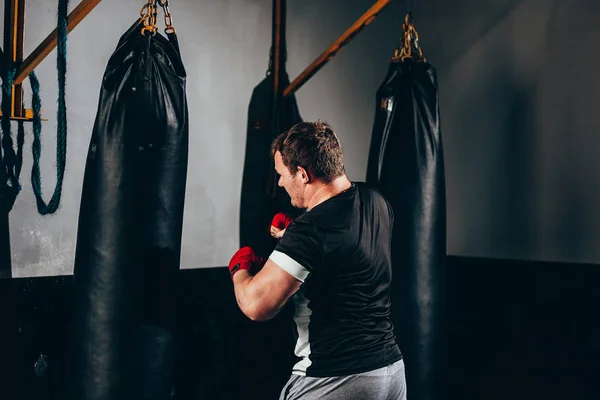 Muž stíhací výcvik v boxovací pytel v tělocvičně — Stock fotografie