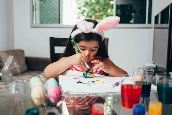 Happy easter! A beautiful child girl painting Easter eggs. Happy family preparing for Easter. Cute little child girl wearing bunny ears on Easter day — Stock Photo, Image