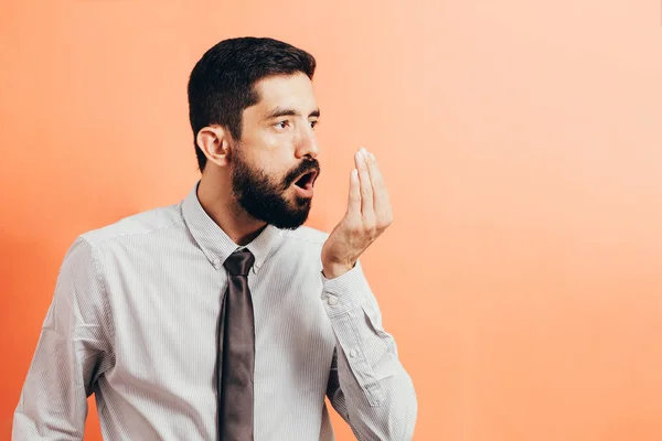 Bad breath. Halitosis concept. Businessman checking his breath with his hand.