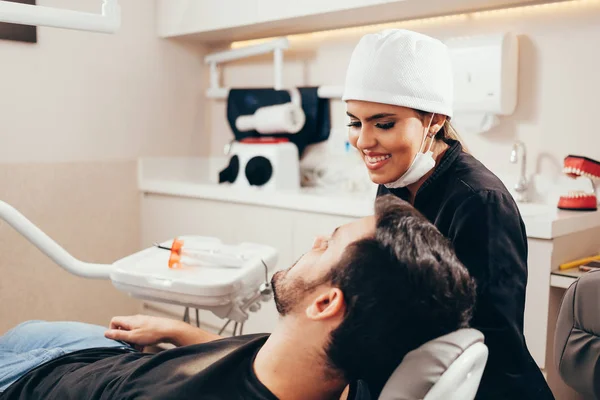 Dentista femenina con paciente masculino en la clínica — Foto de Stock