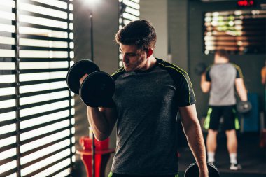 Yakışıklı adam spor salonunda halter çalıyor. Egzersiz konsepti