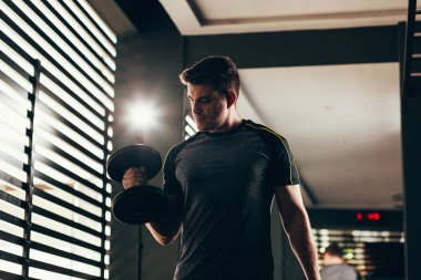 Yakışıklı adam spor salonunda halter çalıyor. Egzersiz konsepti