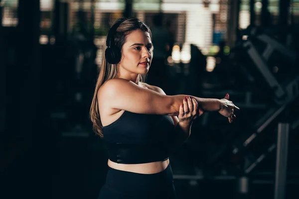 Een jonge vrouw die zich uitstrekt in de sportschool. Workout concept — Stockfoto
