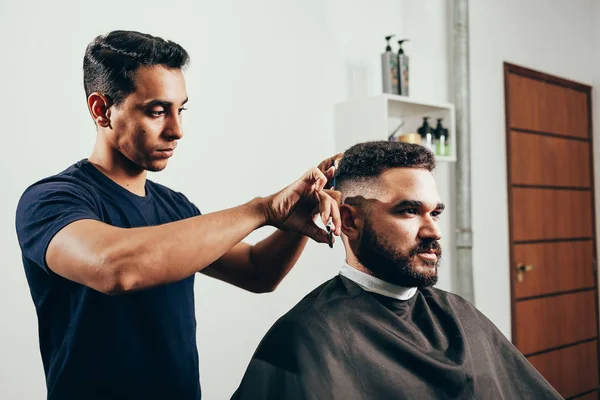 Клиент во время ухода за бородой и волосами в парикмахерской — стоковое фото
