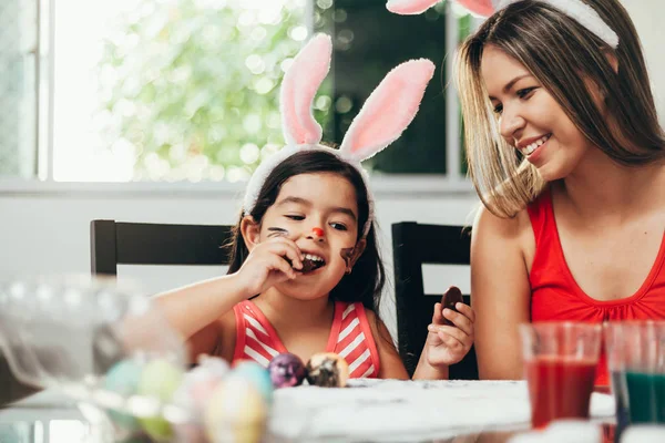 Vrolijk Pasen! Een moeder en haar dochter paaseieren schilderen. Gelukkige familie voorbereiden voor Pasen. Schattig klein kind meisje bunny oren dragen op Paasdag — Stockfoto