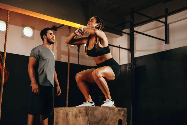 Ajuste mujer joven haciendo un ejercicio de salto de caja. Deportiva haciendo una sentadilla en el gimnasio —  Fotos de Stock
