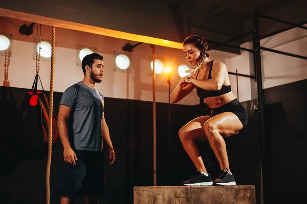 Fit young woman doing a box jump exercise. Sports woman doing a box squat at the gym