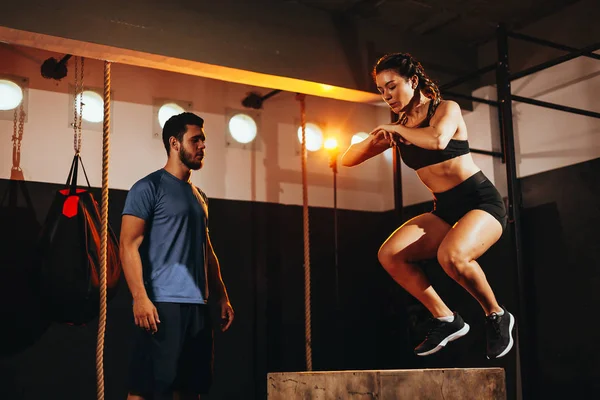 Ajuste mujer joven haciendo un ejercicio de salto de caja. Deportiva haciendo una sentadilla en el gimnasio —  Fotos de Stock