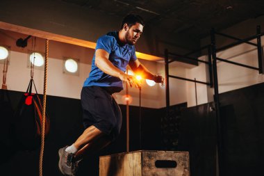 Fit genç adam bir kutu atlama egzersiz yapıyor. Spor salonunda bir kutu çömelme yapıyor spor adam