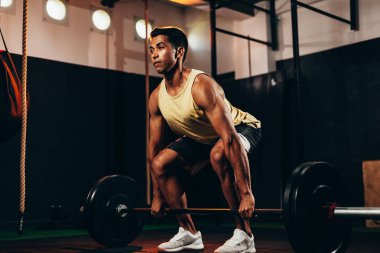 Spor salonunda ağır egzersizler yapan kaslı adam. Sağlık kulübünde halter yapan genç adam