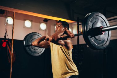 Spor salonunda ağır egzersizler yapan kaslı adam. Sağlık kulübünde halter yapan genç adam