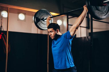 Spor salonunda ağır egzersizler yapan kaslı adam. Sağlık kulübünde halter yapan genç adam