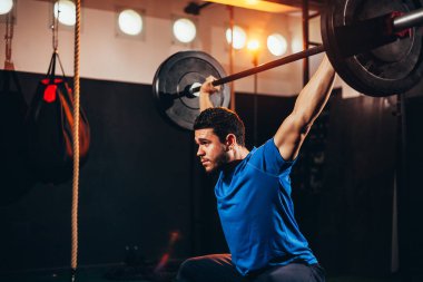 Spor salonunda ağır egzersizler yapan kaslı adam. Sağlık kulübünde halter yapan genç adam