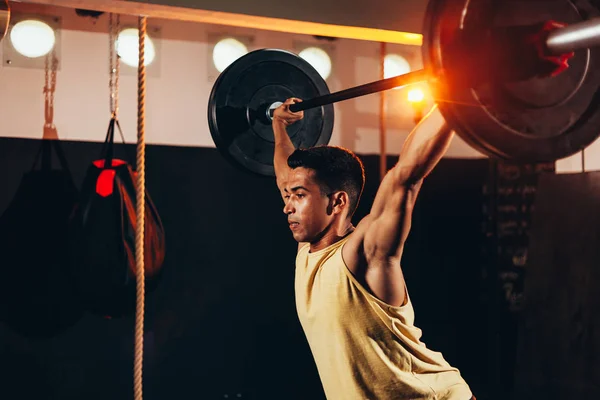 Svalnatý muž v tělocvičně dělá těžký cvičení. Mladý muž dělá ve zdravotnickým klubu zvedání váhy — Stock fotografie
