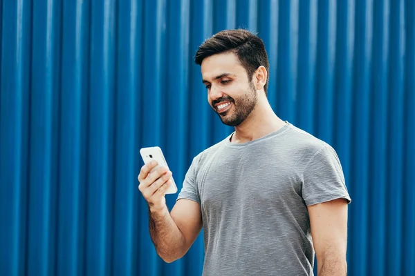 Jongeman loopt op straat en gebruikt zijn smartphone — Stockfoto