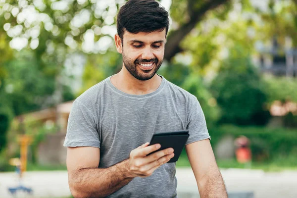 Young man reading e-book in the park