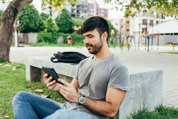 Молодий чоловік читає електронну книгу в парку — стокове фото
