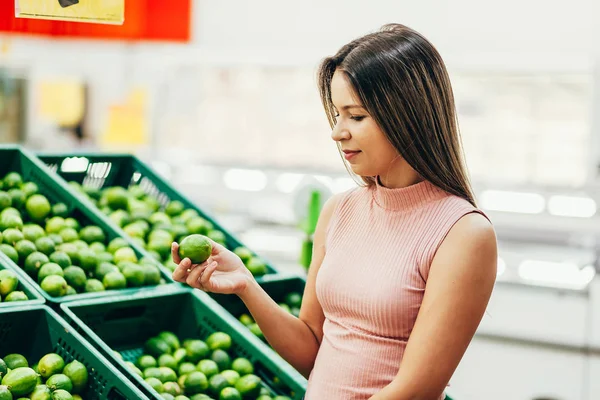 Young woman buying vegetables in the supermarket
