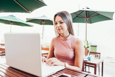 Bir kafede dizüstü bilgisayar kullanan güzel genç kadın